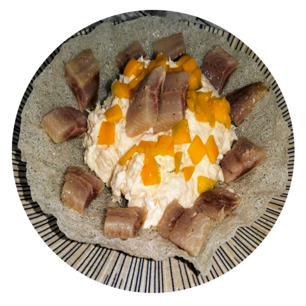 Ensaladilla de merluza y langostinos, con arenque ahumado y mango, sobre oblea de arroz